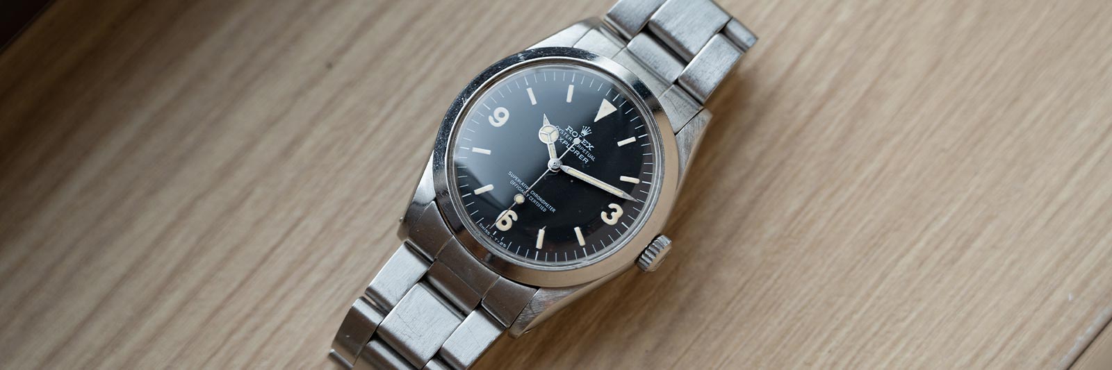 stainless steel rolex explorer on a wooden table
