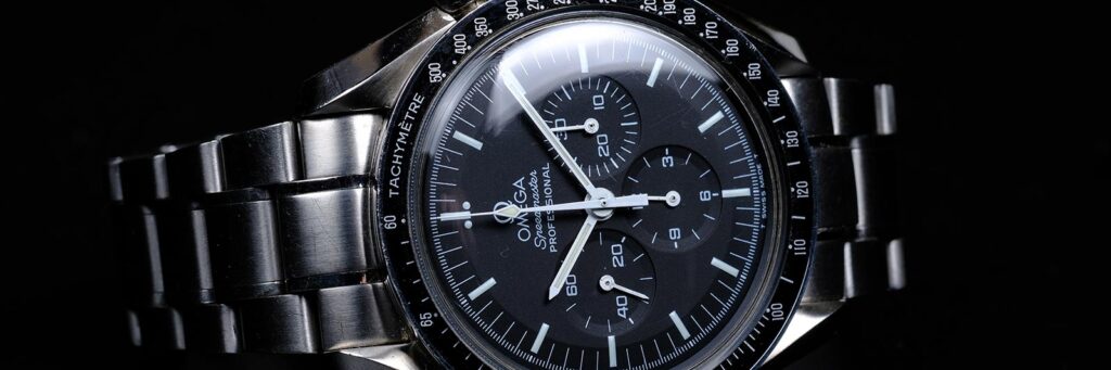 stainless steel omega watch laying on its side