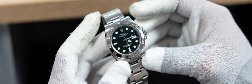 professional watch refinisher holding a stainless steel Rolex watch