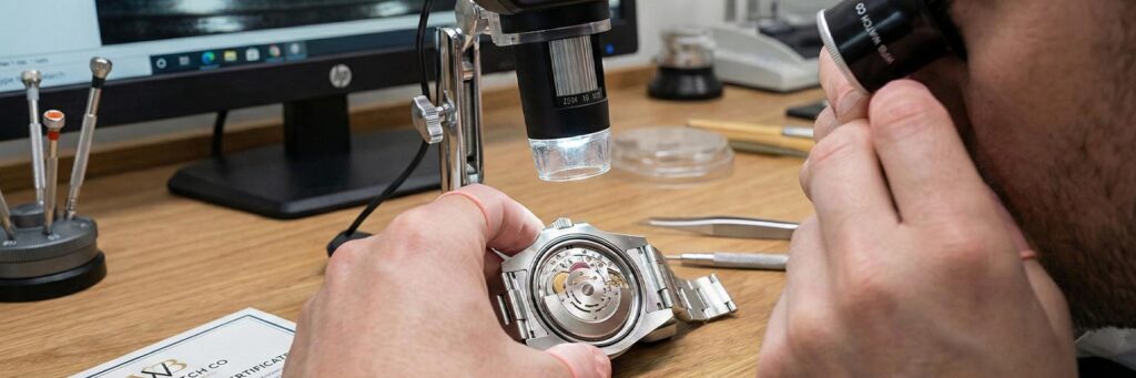 Professional watchmaker examining a Rolex movement with a loupe for authentication.
